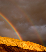 Double rainbow over desert hills.