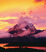 Cloud-shrouded mountain and river at sunset.