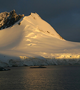 Mountain glacier rising above cold waters.