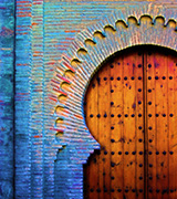 Old wooden Spanish door with a blue arched frame.