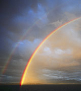 Photo of a double rainbow against blue clouds.