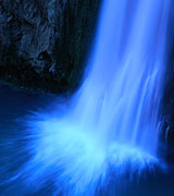 Photo of a high waterfall with blurred white spray against a blue background.