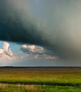 Rain and dark clouds over green fields.