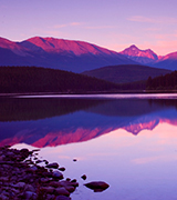 Mountains reflected in a still lake at sunrise.
