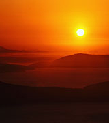 Photo of a deep orange sunset over distant dark hills.