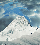 Sharp mountain peak surrounded by clouds.