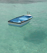 Rowboat floating in clear green waters.